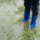 child in blue boot standing in flooded yard